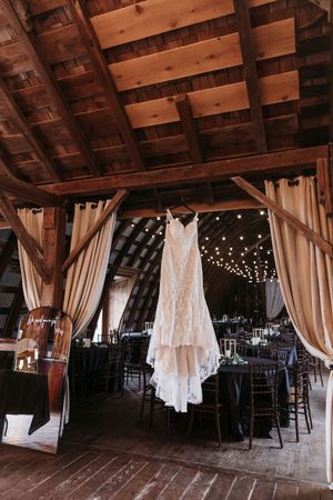 Rustic barn interior decorated for a wedding with hanging lights and white curtains.