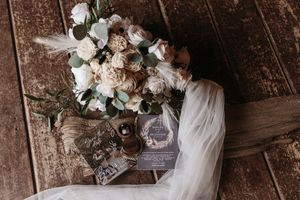 A romantic wedding couple embraces in a rustic wooden barn setting with elegant floral decorations.