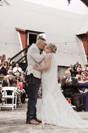 A romantic first dance sequence at a rustic barn wedding venue with string lights and guests watching from their seats.