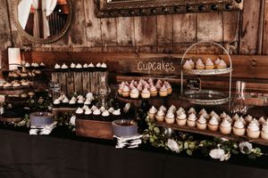 A rustic wooden wall display features rows of white ceramic cupcake stands with elegant floral decorations.