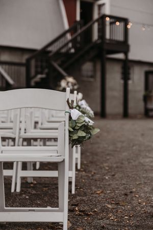 Row of white wooden chairs set up for an outdoor wedding ceremony.