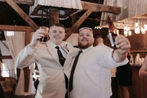 Wedding reception celebration inside a rustic barn venue with string lights.