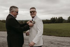 Two people share an emotional moment outdoors on a cloudy day in an open field.