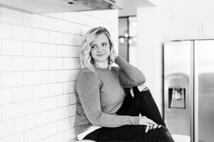 Black and white photo showing someone looking thoughtfully to the side while seated in an interior space.