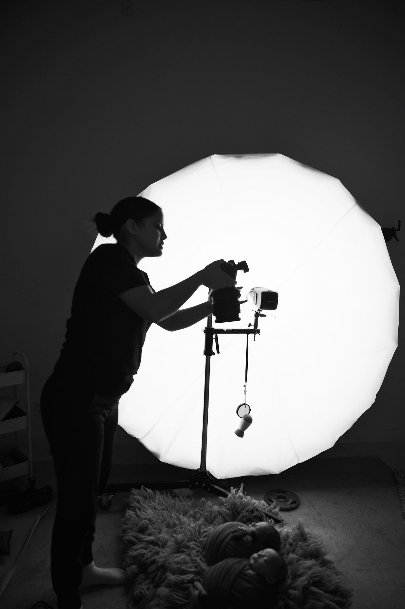 A sequence of black and white silhouettes showing a photographer setting up lighting equipment in a studio.