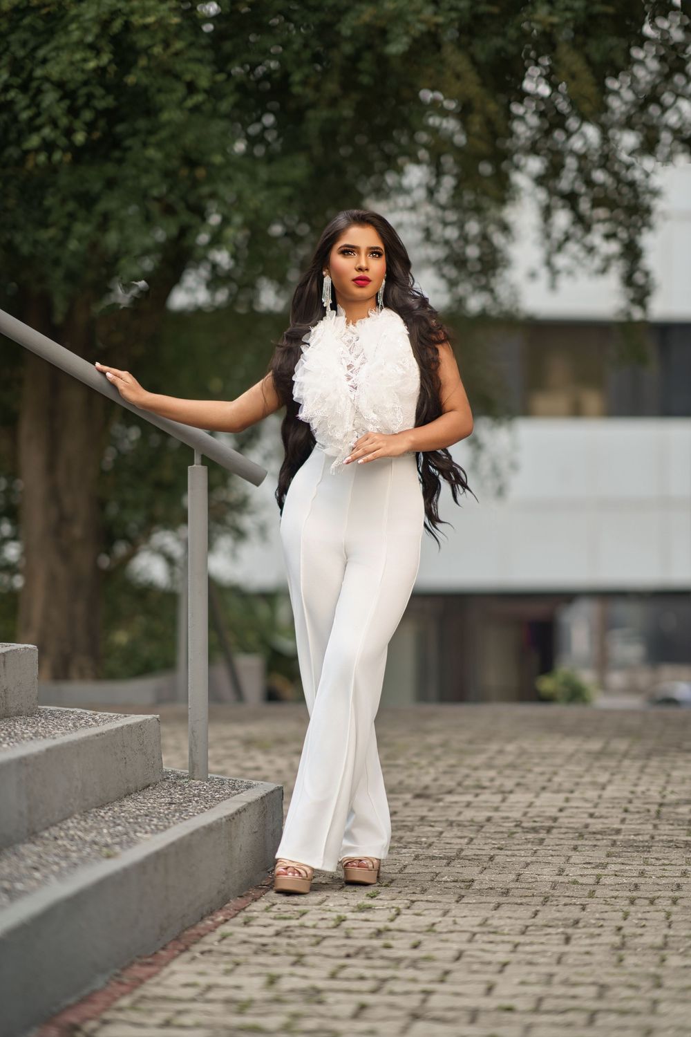 A model in a flowing white gown strikes graceful poses on stone steps with trees in the background.