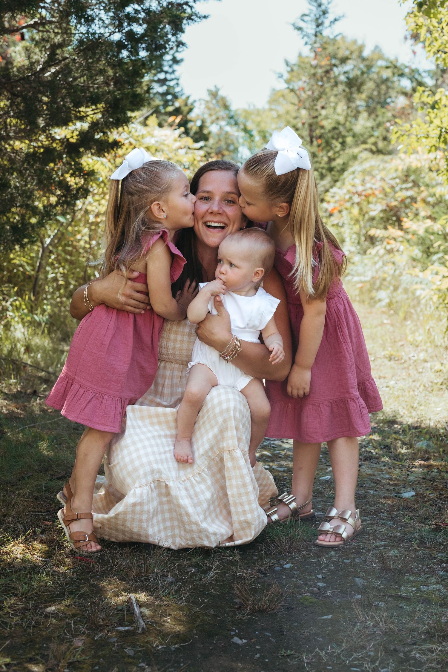 Sweet outdoor family photoshoot with matching pink dresses and playful poses.