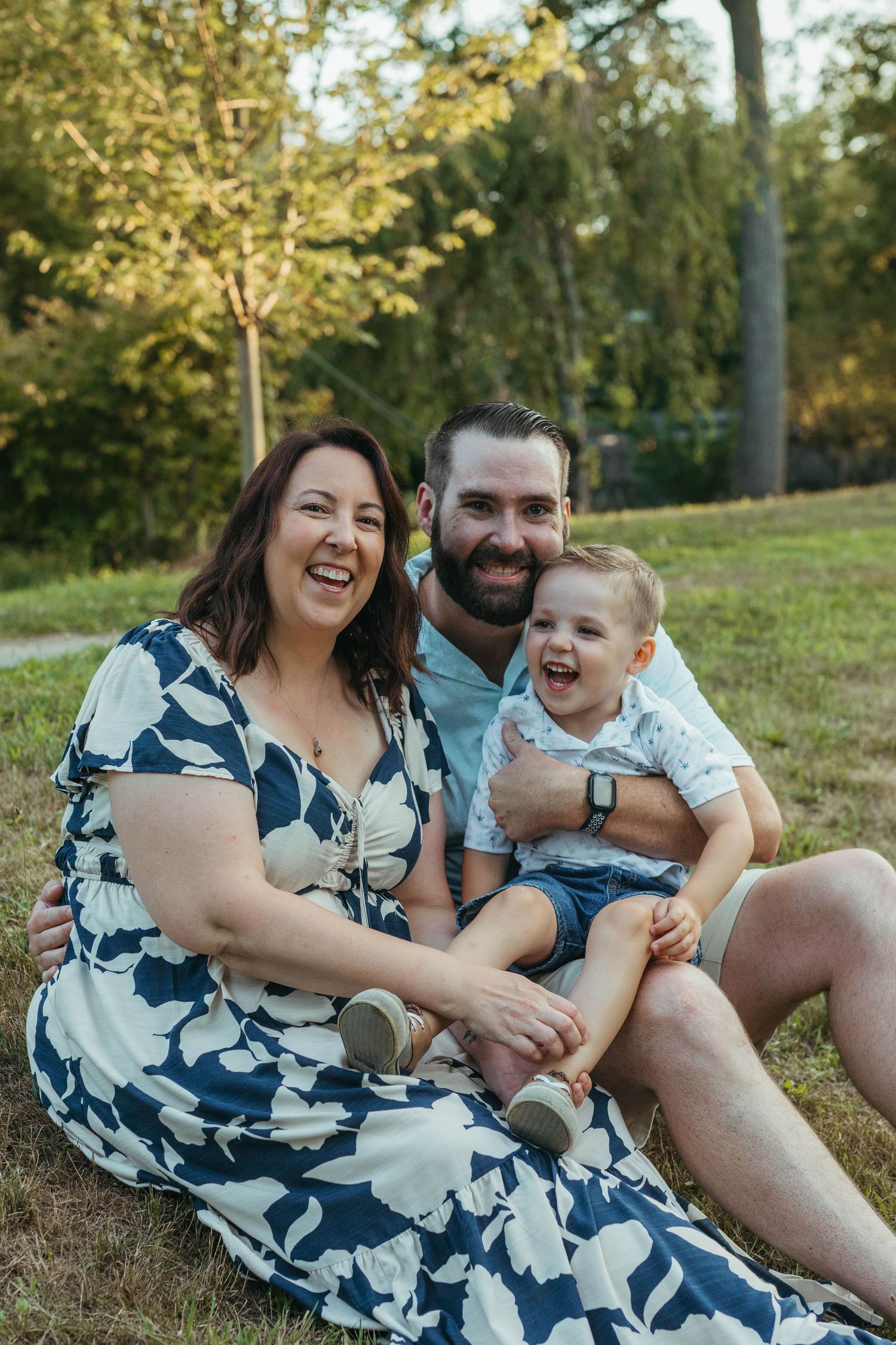 Candid family photography session showing joyful moments on grassy hillside in summer.