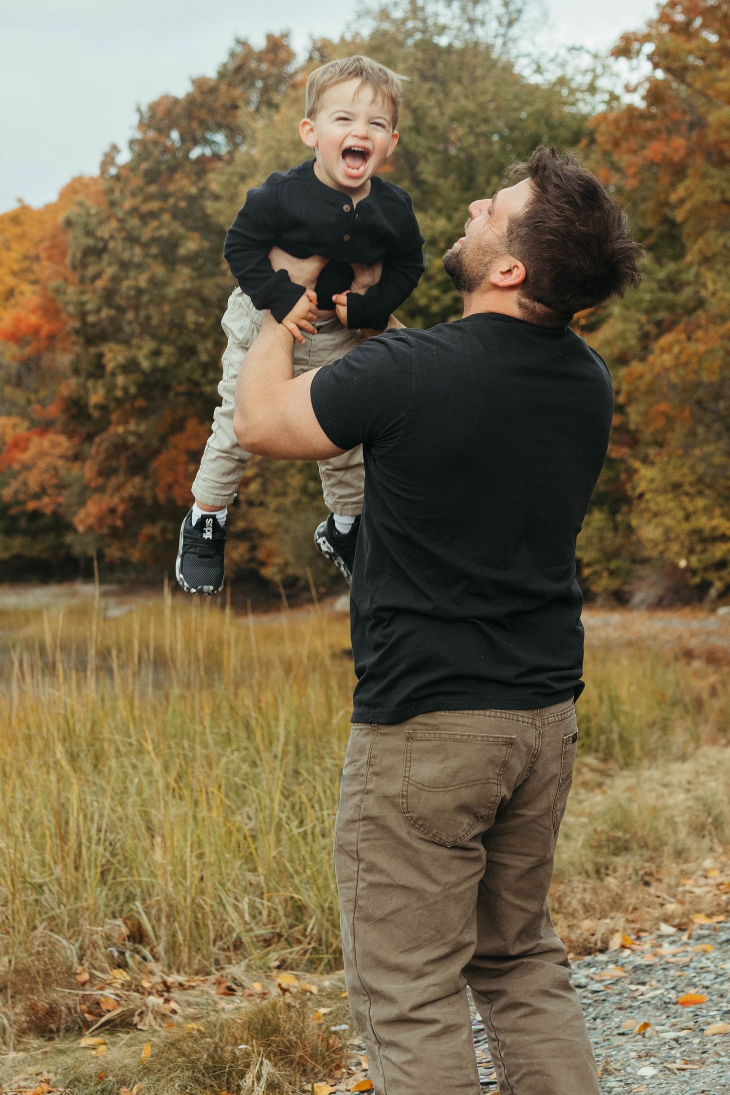Playful autumn photoshoot showing joyful moments between parent and child in fall foliage.