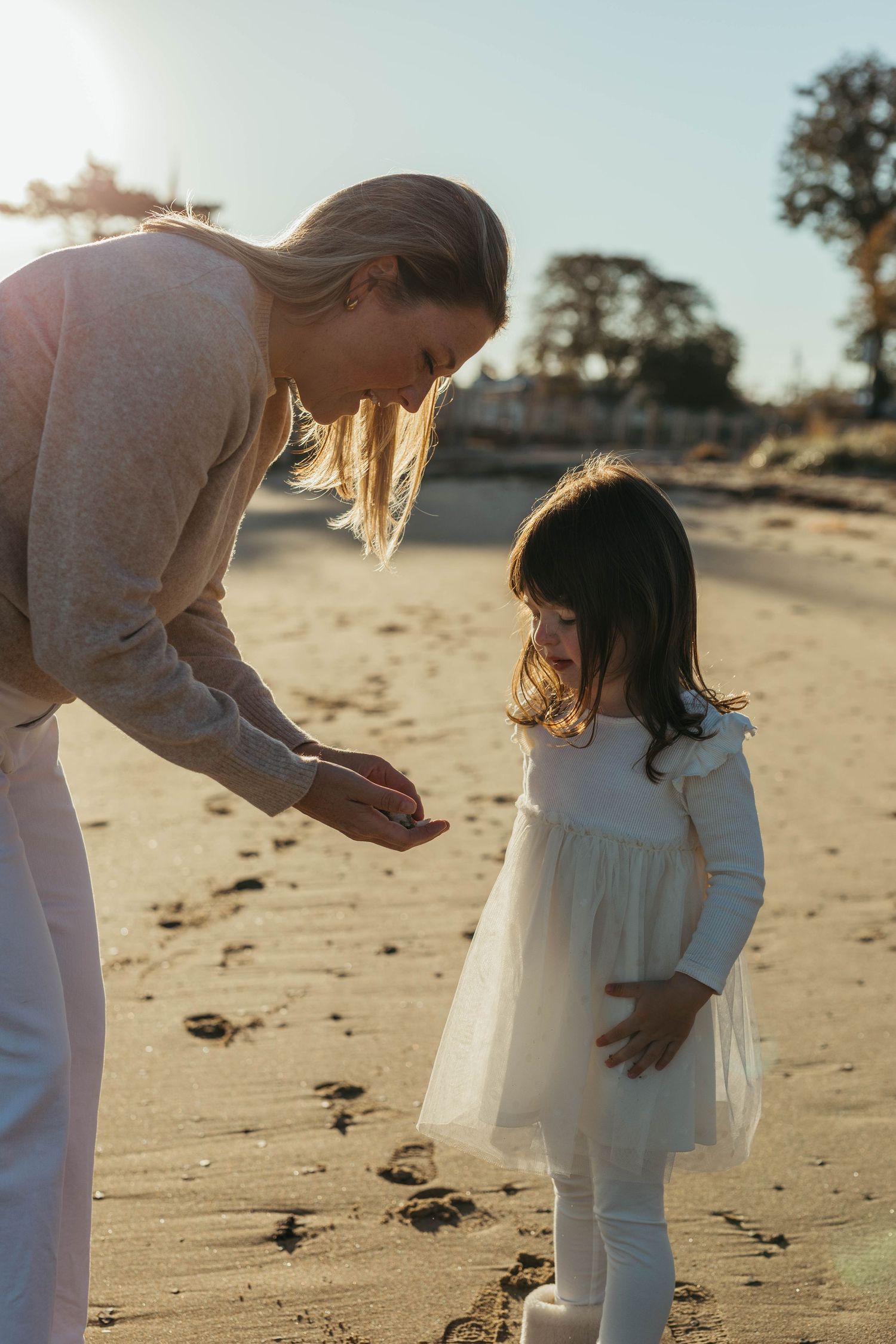 Tender beach photography session capturing gentle parent-child interactions at sunset.
