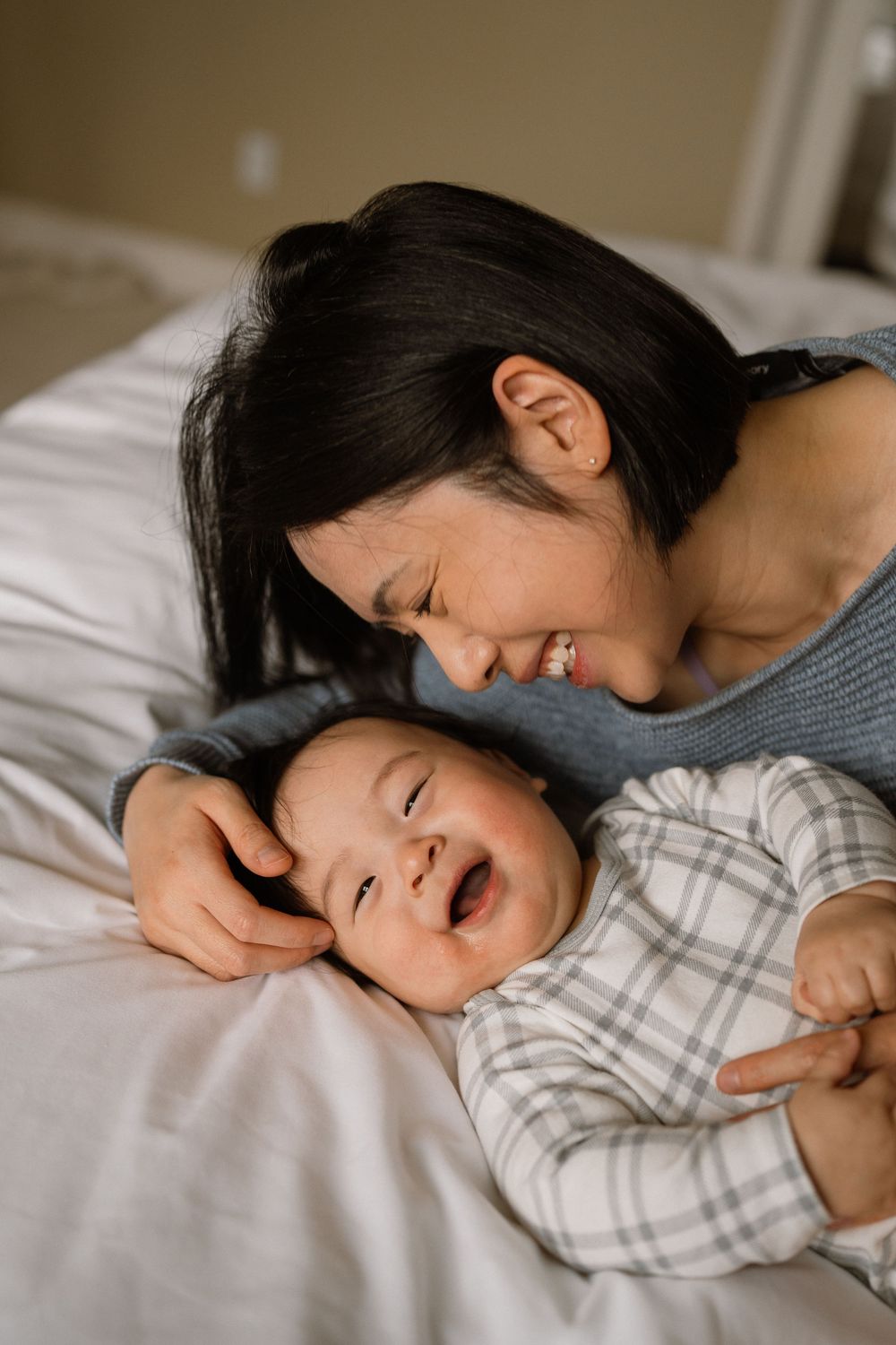 Two people sharing a tender moment while resting together on white bedding.
