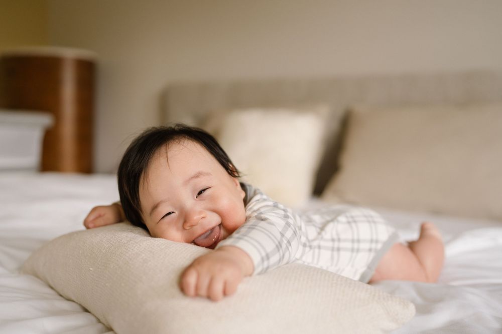 Person resting peacefully on white sheets with natural light streaming through window.