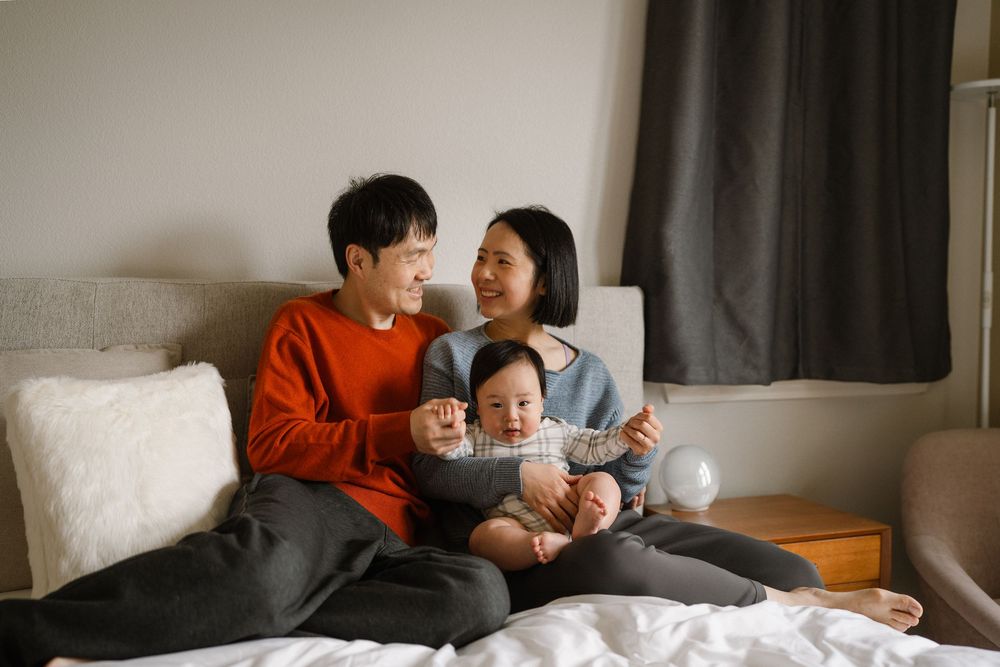 A family shares a tender moment together while relaxing on a cozy gray couch.