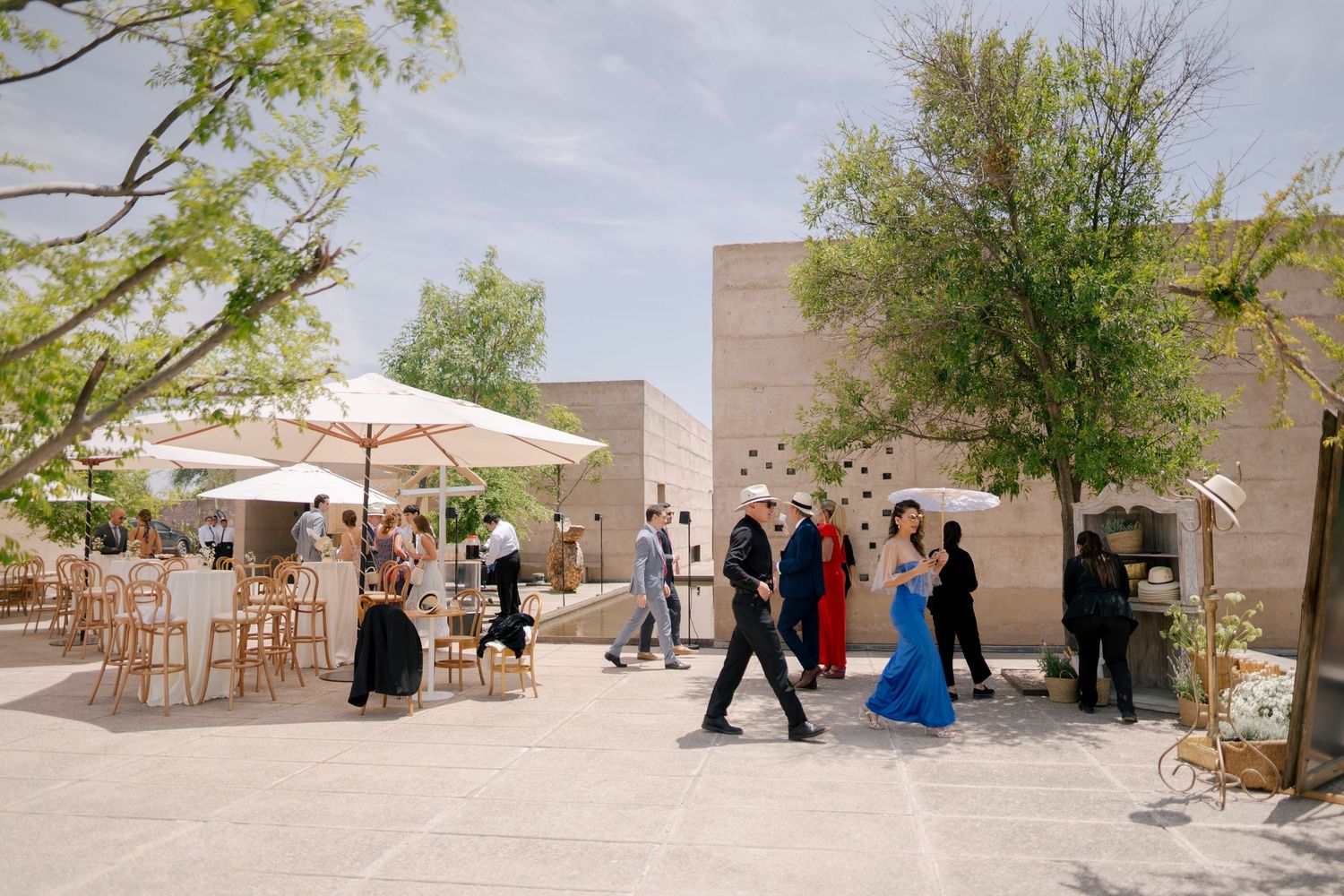 Outdoor wedding venue with stone walls and desert landscaping features a row of white umbrellas and chairs set up for ceremony.