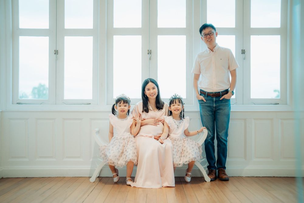 A bright and airy indoor photoshoot with a family in white and pastel outfits.