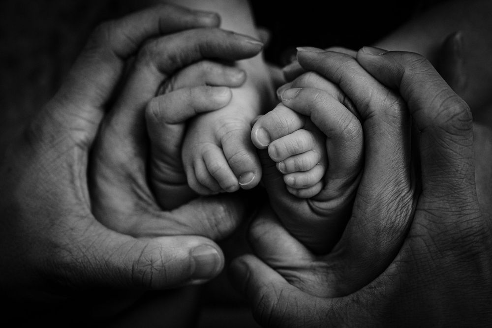 Black and white image showing multiple hands joined together in unity.