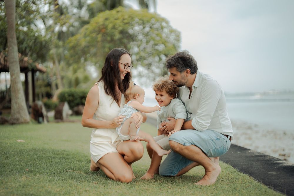 A family enjoys a playful moment together on a beach during sunset.