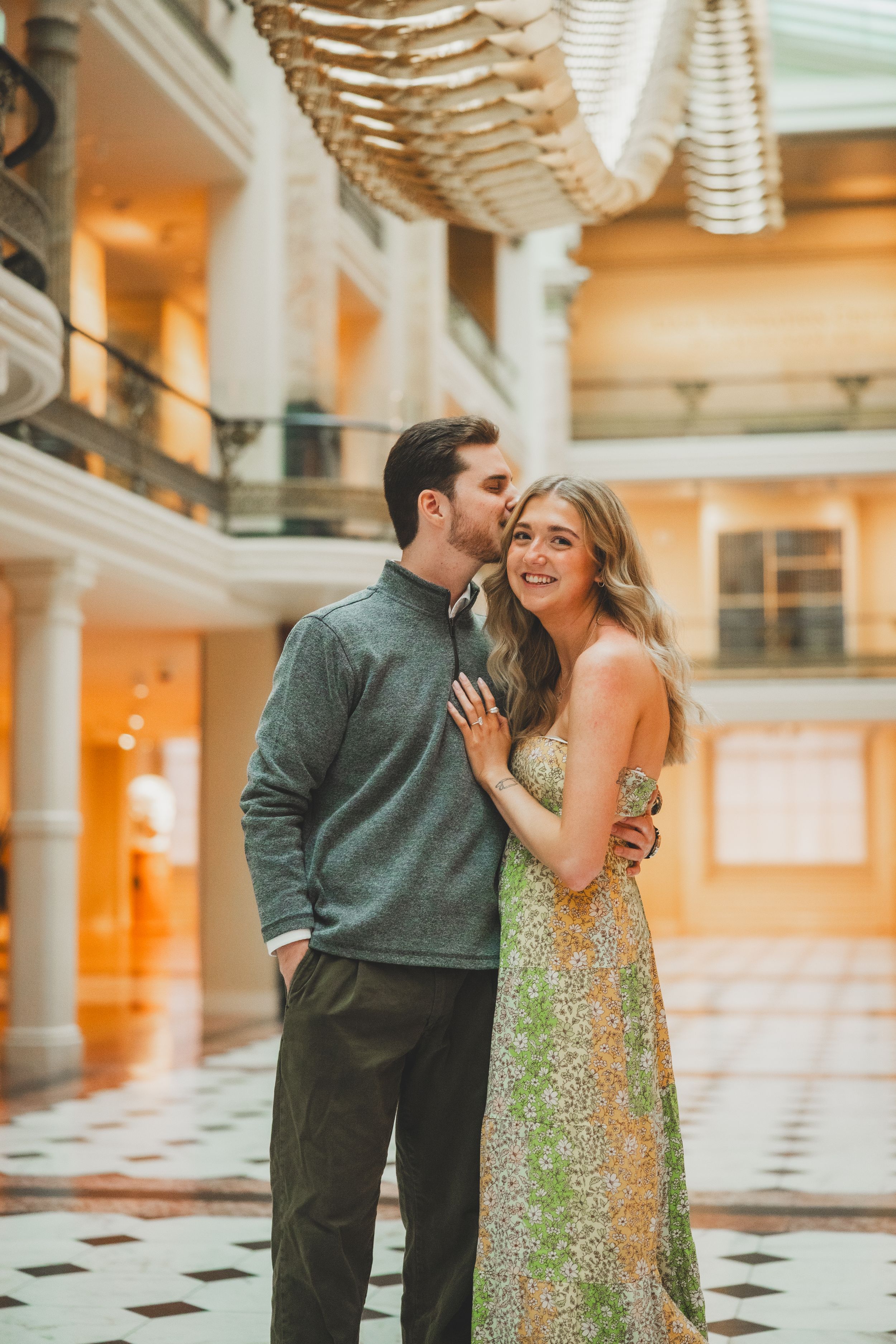 A couple shares a joyful moment together in a grand indoor space of the National Portrait Gallery,  a dc winter proposal location