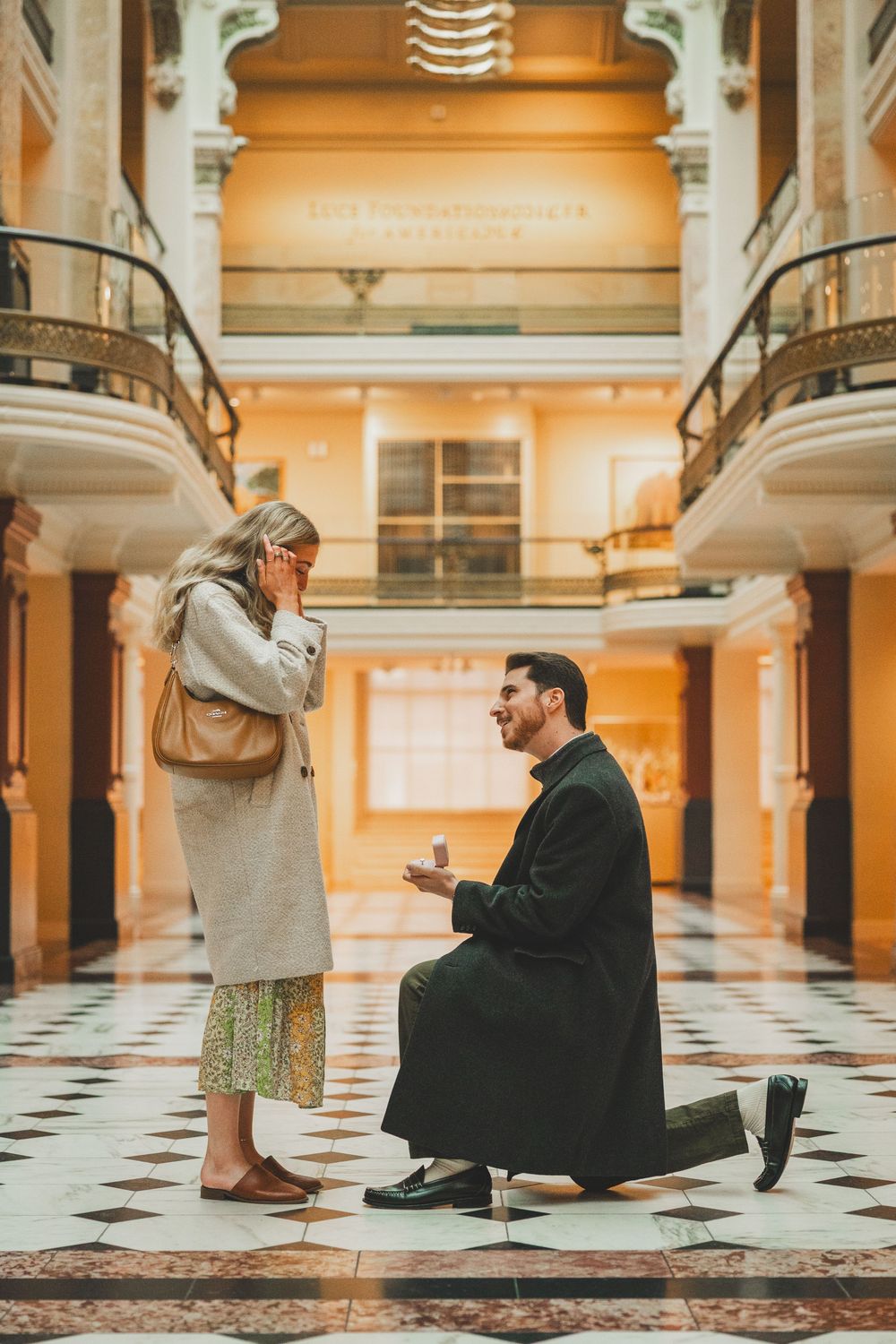 A romantic proposal moment captured in an elegant vintage building with checkered floors and ornate balconies of National Portrait Gallery