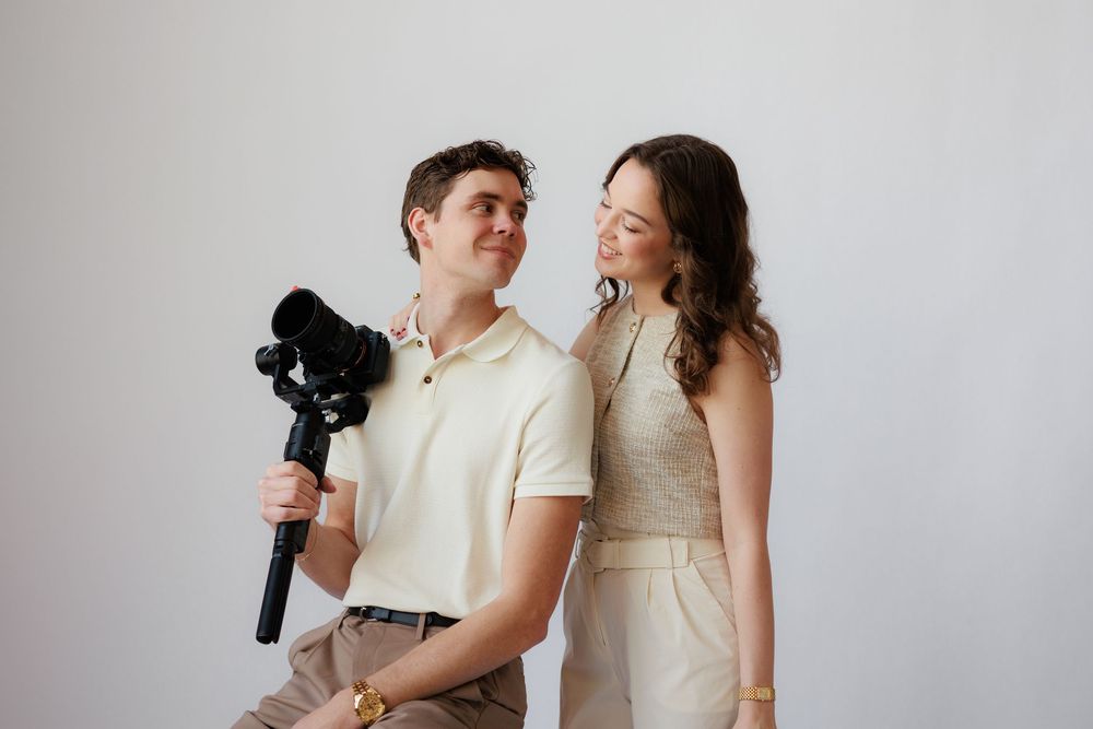 A couple in light-colored outfits shares a joyful moment while posing together during a photo session.