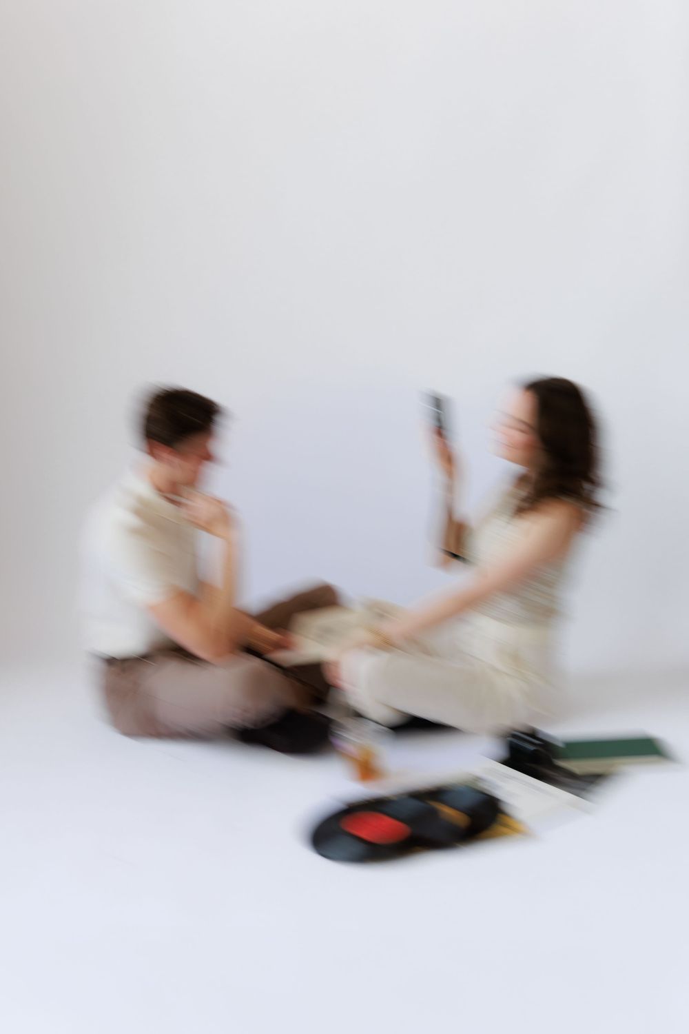 Motion blur sequence shows two people sitting on floor having an animated discussion with books and papers.
