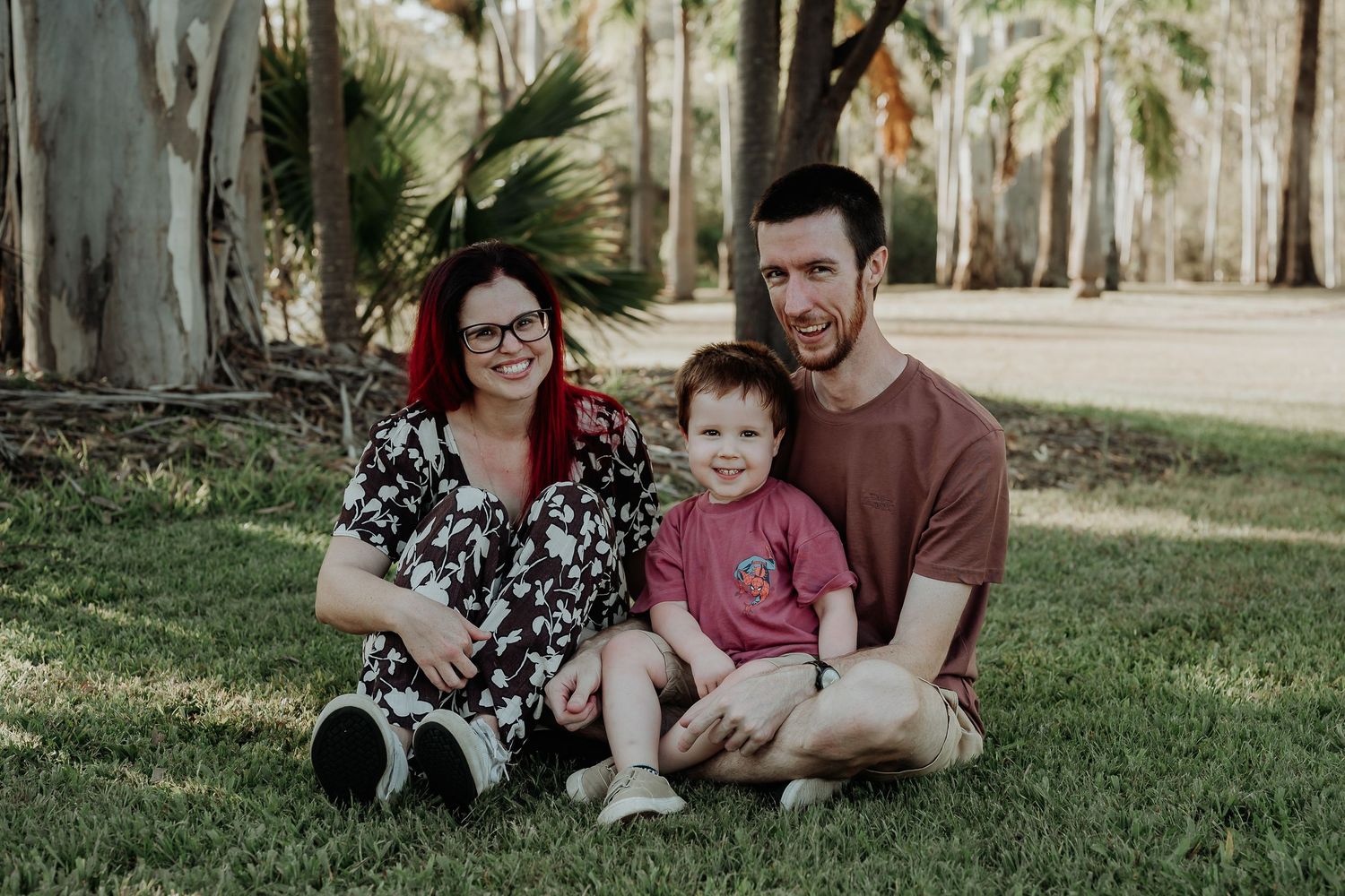 Family relaxing together on lush green grass under palm trees at toondoon botanic gardens.