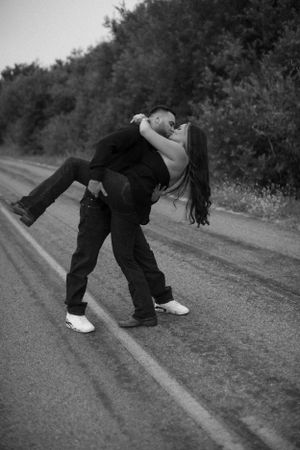 Romantic black and white dip kiss pose on country road.