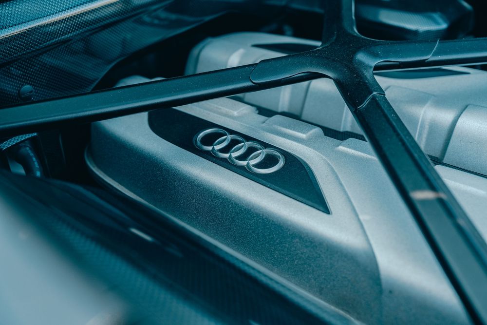 Close-up view of an Audi engine bay showing the metallic logo and engine cover.