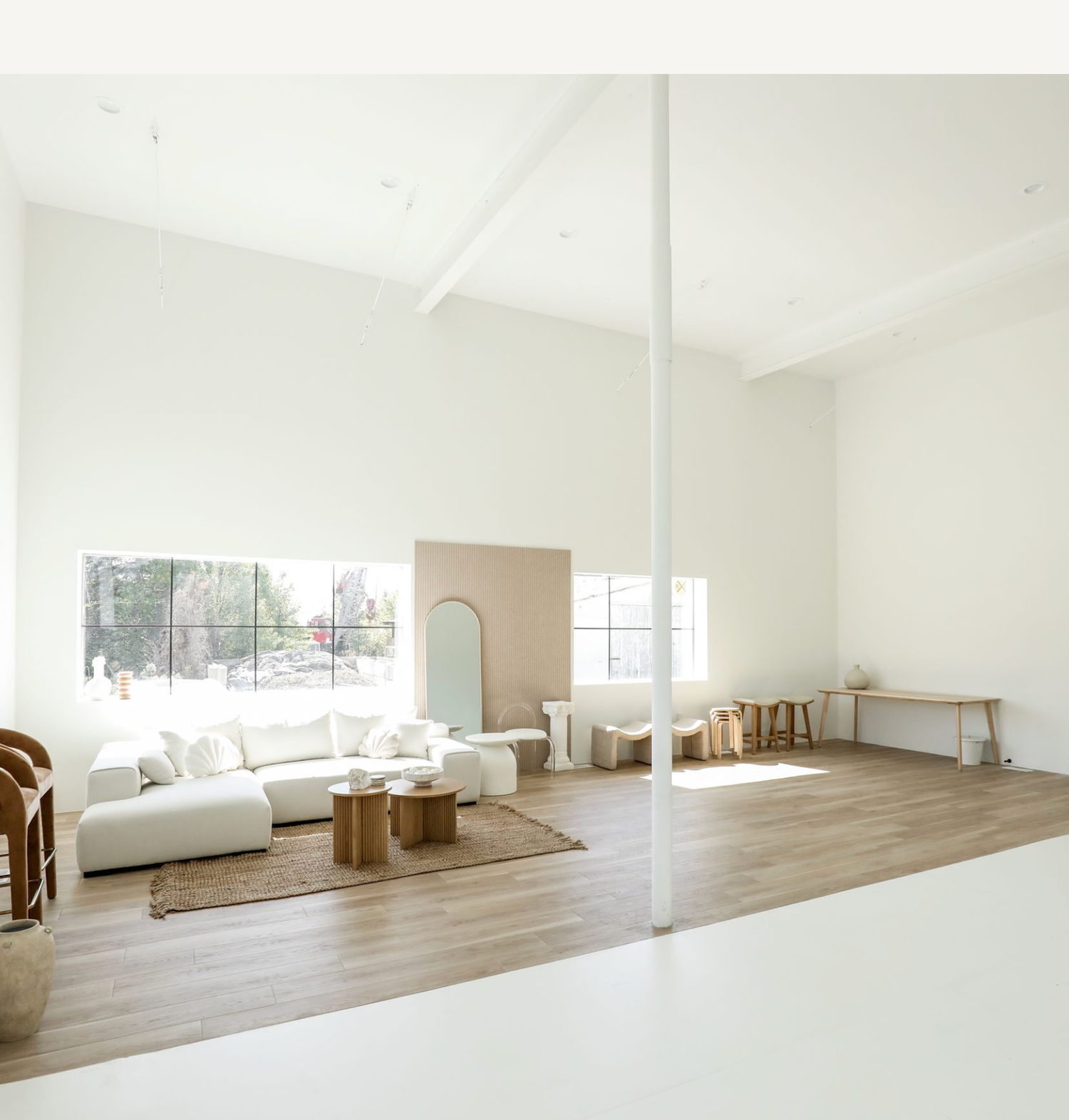 Modern minimalist dance studio with white walls, hardwood floors, mirror wall, and natural light streaming through windows.