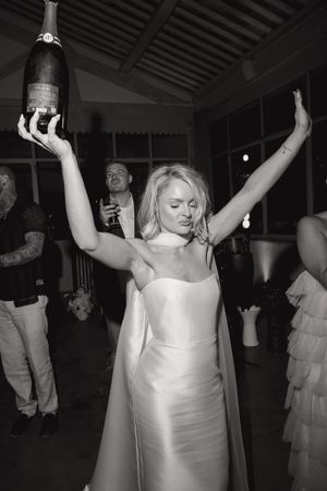Wedding reception guests dancing and celebrating with raised arms on the dance floor.