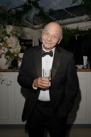 Guests in formal black tie attire enjoying drinks at an evening wedding reception.