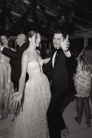 Wedding celebration scene showing dancing and festivities in a decorated venue with string lights overhead.
