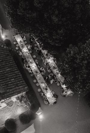 Aerial view of an outdoor dining setup at night with multiple tables arranged in rows illuminated by string lights.