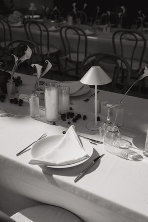 Elegant table setting with white linens and glassware for a formal dining event.