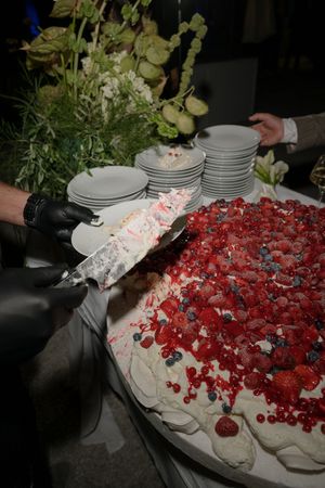 A large white wedding cake decorated with fresh red berries and whipped cream.
