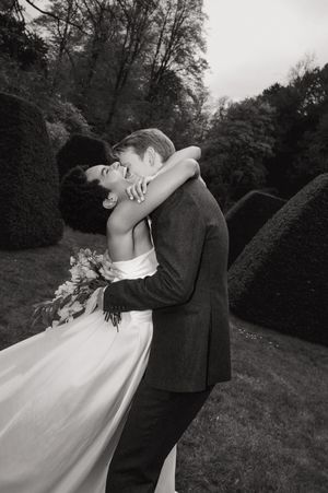 A romantic black and white photo series of a couple dancing and embracing outdoors in formal wedding attire.