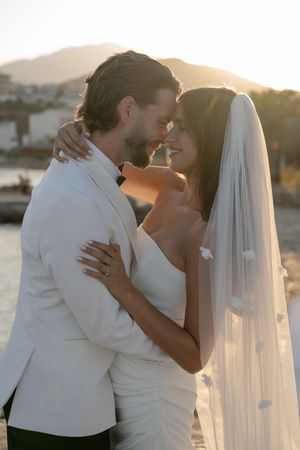 Newlywed couple shares romantic sunset kisses by the waterfront in a series of intimate wedding photos.