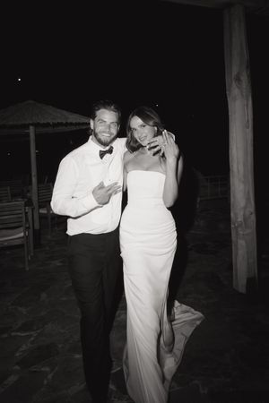 A couple dancing together in formal attire at a nighttime wedding reception.