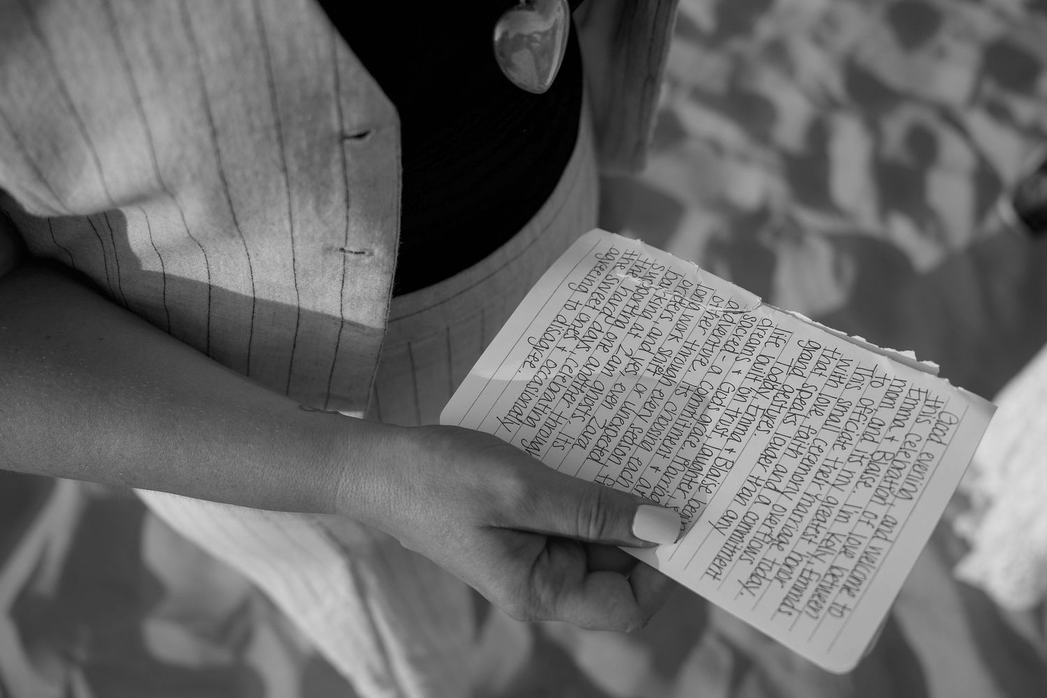 A person holds a handwritten note or letter with dense text written in black ink on white paper.