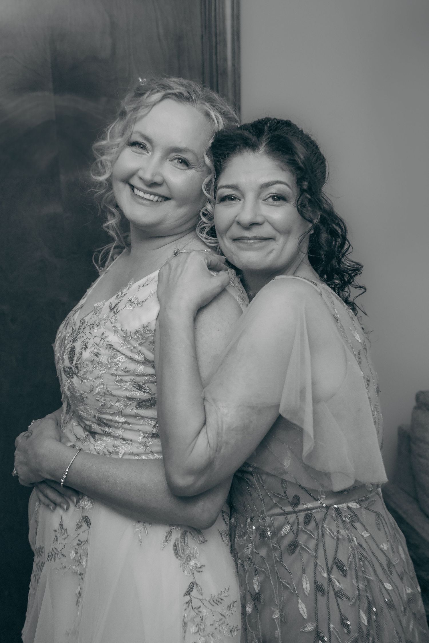 Two people in elegant dresses share tender moments in a black and white photo series.