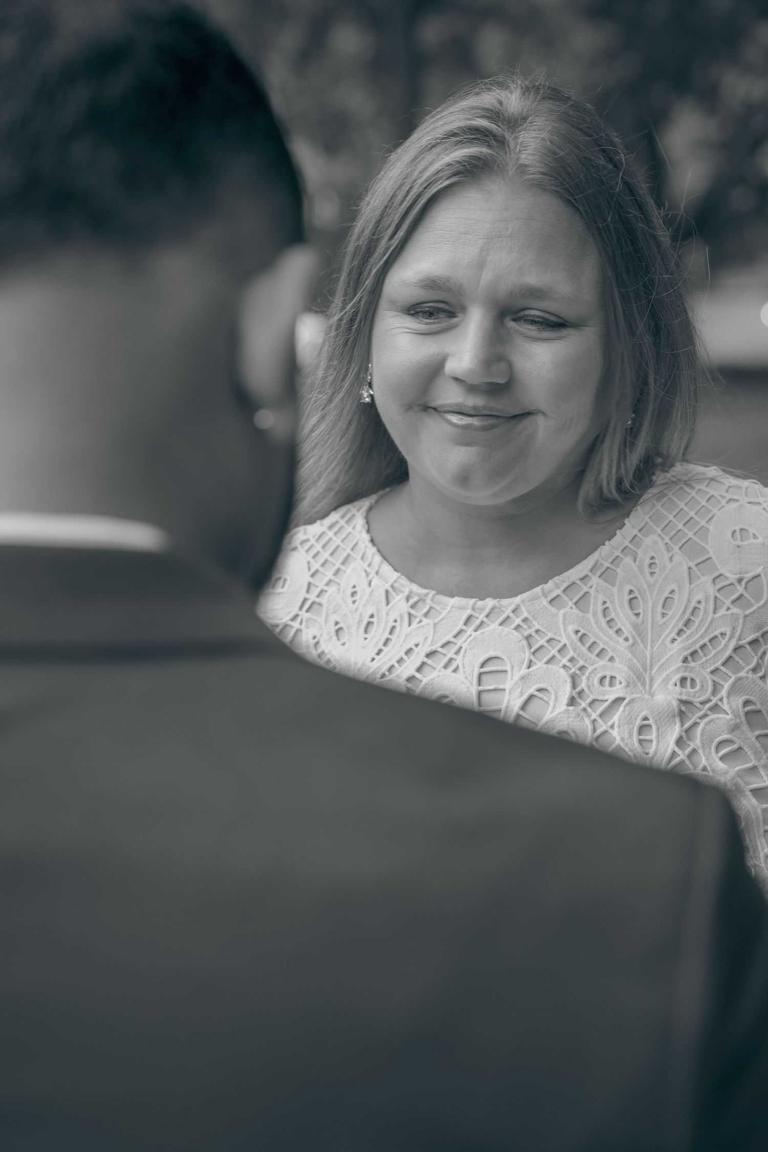 A black and white portrait series showing a person in a lace top looking down and smiling softly.