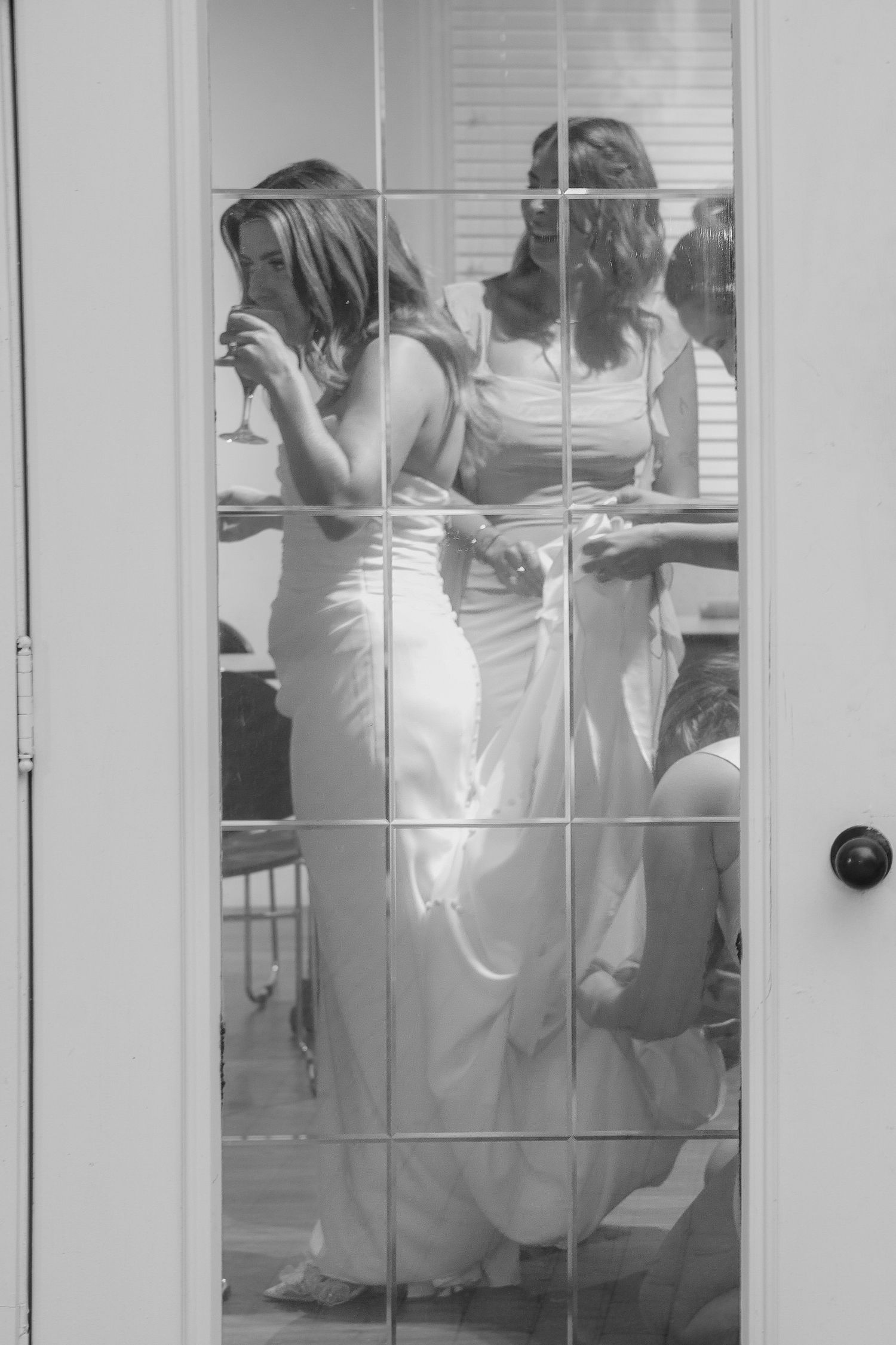 Black and white image showing nurses in white uniforms seated in a classroom through glass windows.