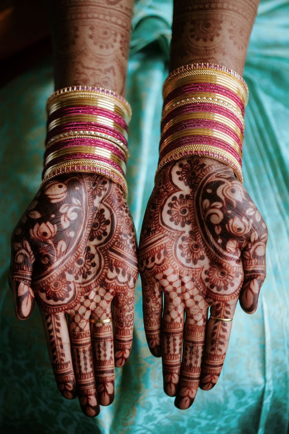 Detailed mehndi designs on palms with traditional Indian bangles and jewelry.