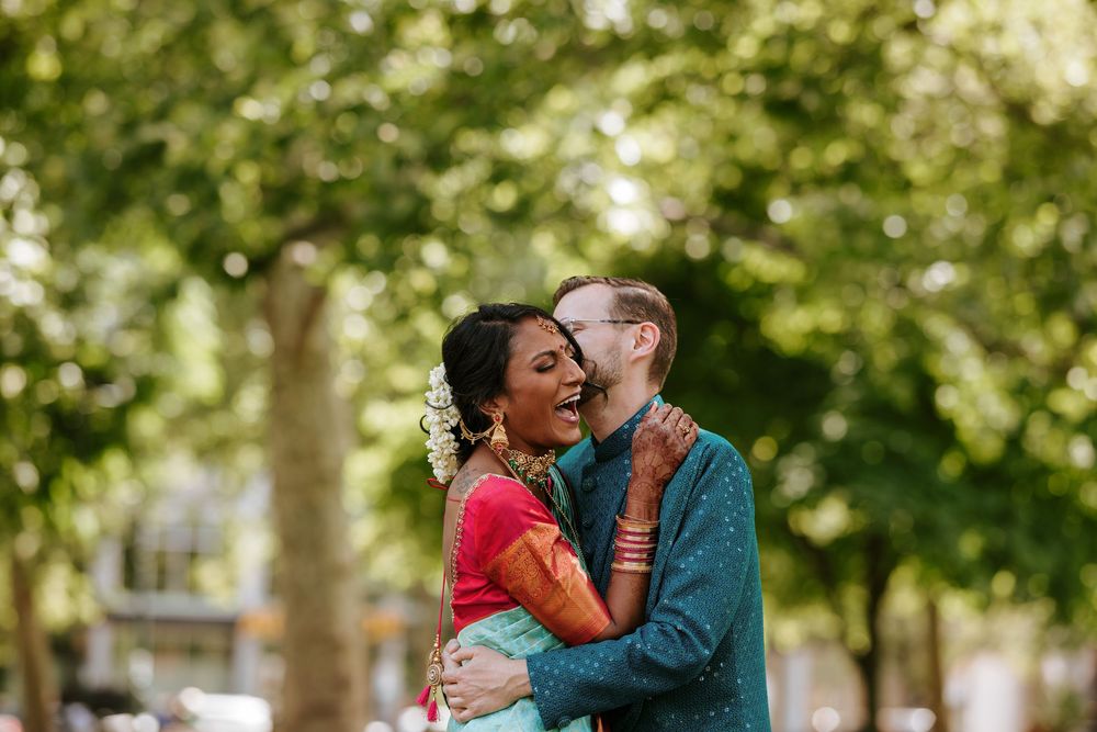 A couple shares romantic moments in a park setting with trees and natural lighting.