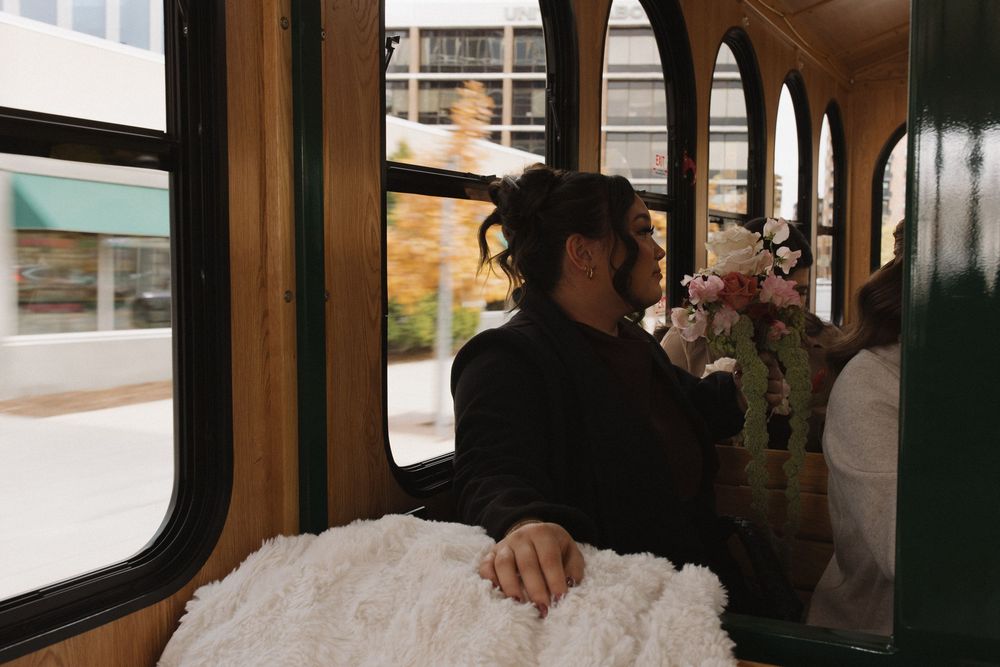 A person's hand rests on the window of a moving train or bus while passing through an urban area.