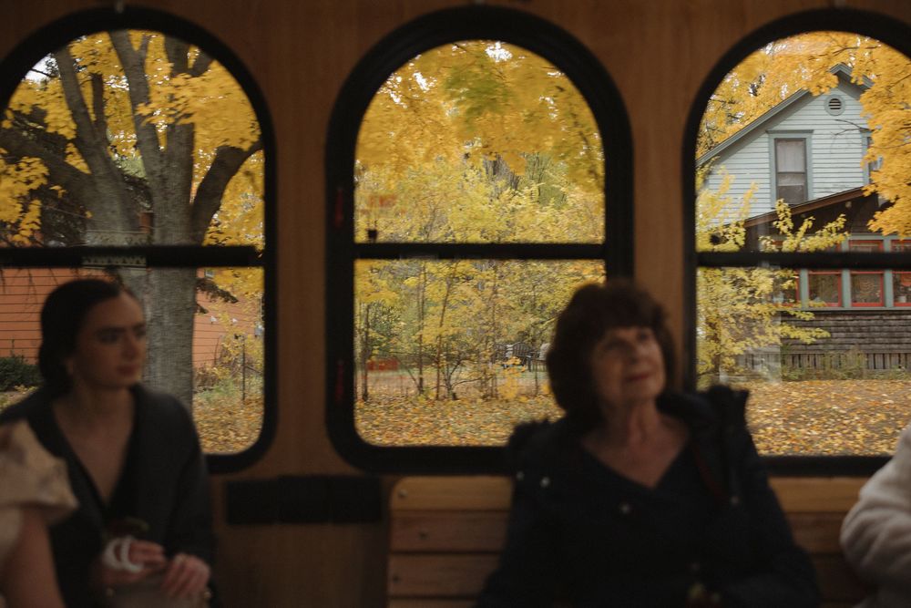 Autumn foliage frames the windows of a vintage bus interior during a scenic tour.