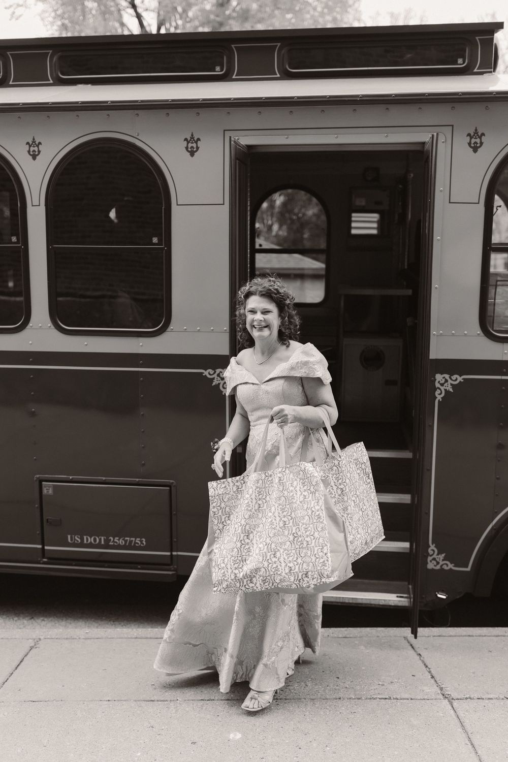 Black and white photo of a vintage bus with passengers getting on and off in an urban setting.