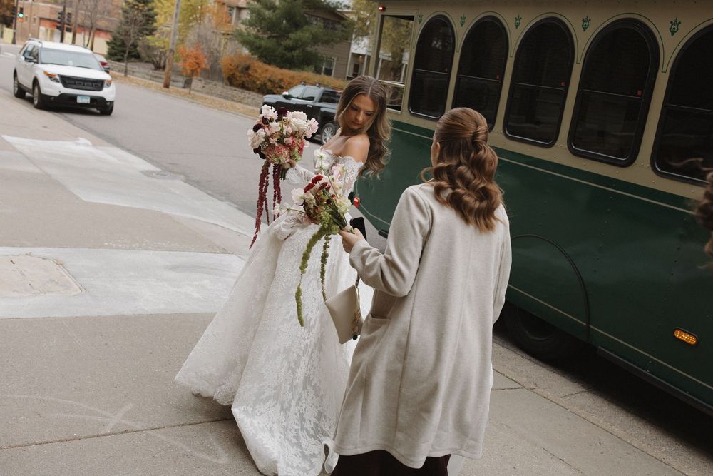 Wedding party poses together outside a historic building with arched columns and stone architecture.