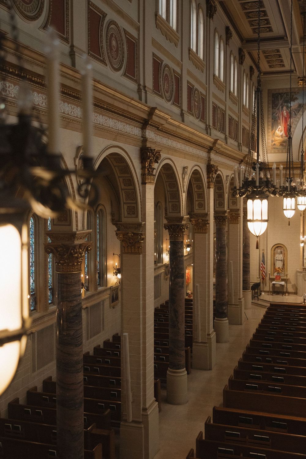 Interior view of an ornate church sanctuary with rows of wooden pews and sunlight streaming through tall windows.