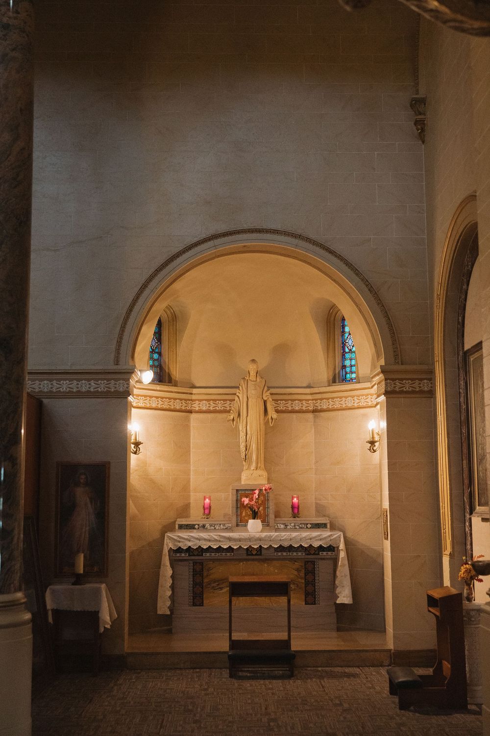 Interior panorama of a stone church sanctuary with arched ceilings, altar, and warm lighting.